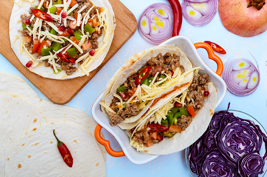 Spicy Mexican tacos with minced meat, mashed beans, vegetables,